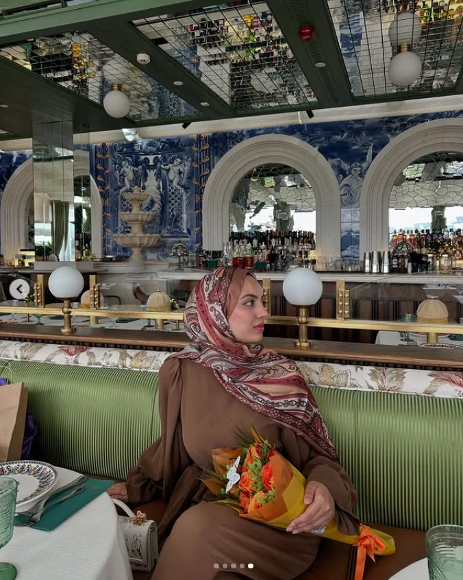Ebadah Ayoubi’nin kahverengi kıyafetli, çiçek tuttuğu kişisel fotoğrafı